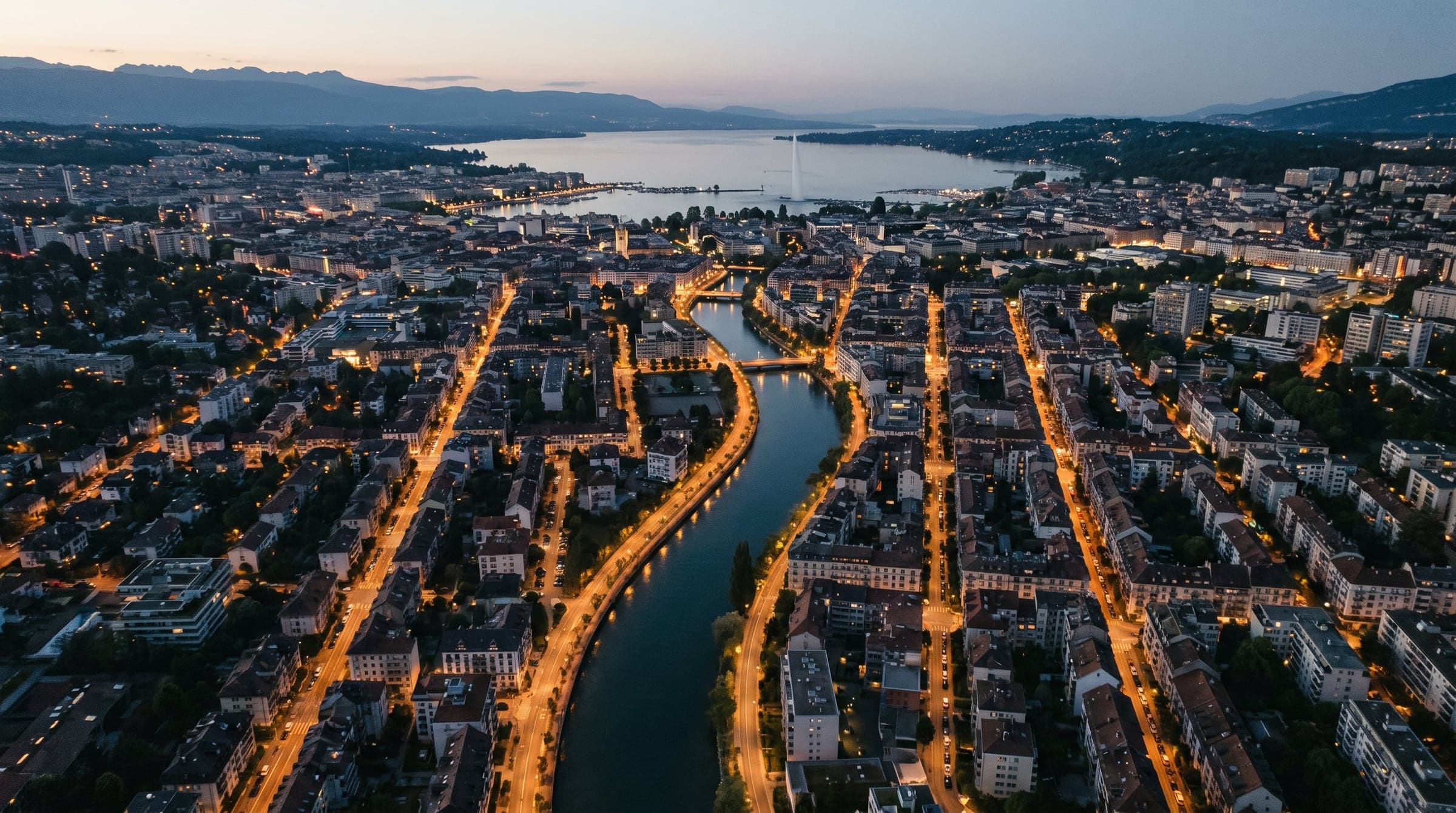 Vue aérienne de Genève au crépuscule, quartiers de Carouge et l’Arve éclairés